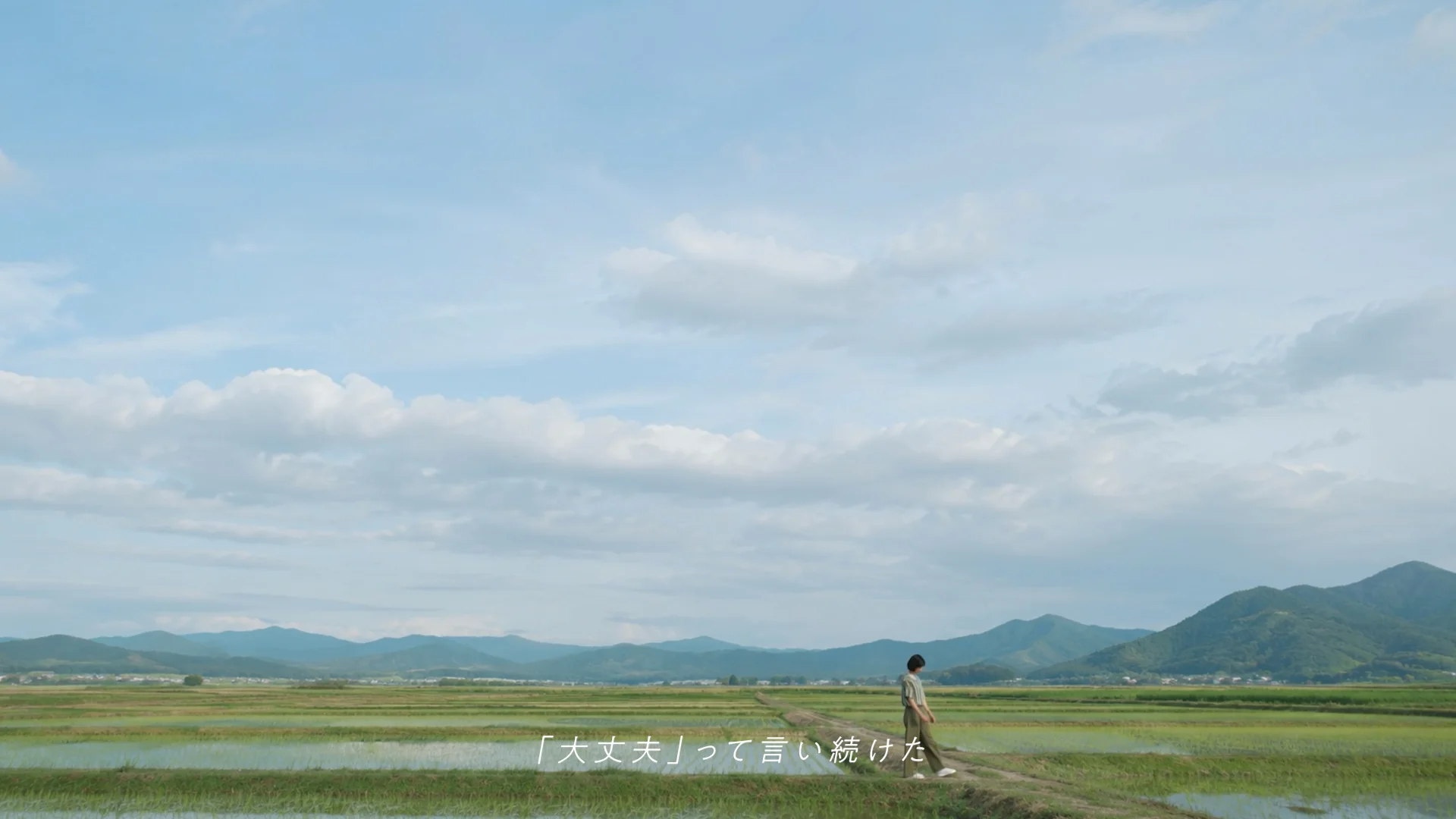 広い田園風景の中にいるぐら。『大丈夫』って言い続けた、という字幕のMVカット
